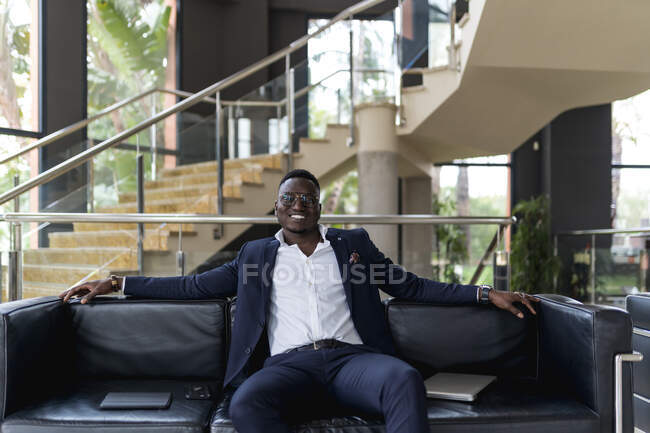Lächelnder männlicher Unternehmer sitzt auf Sofa in Hotellobby — Stockfoto