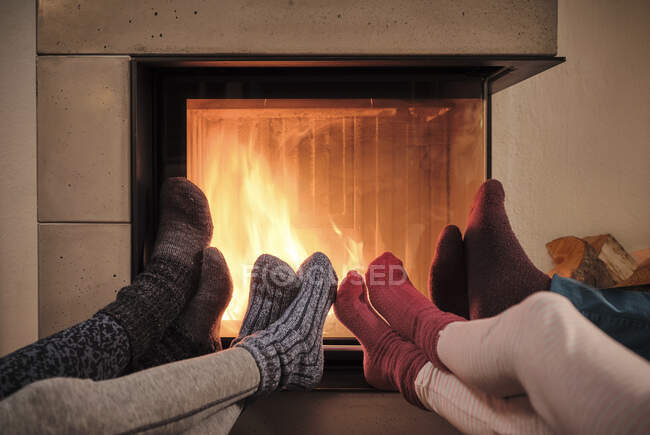 Family warming up feet in woolen socks by fireplace in living room — Stock Photo