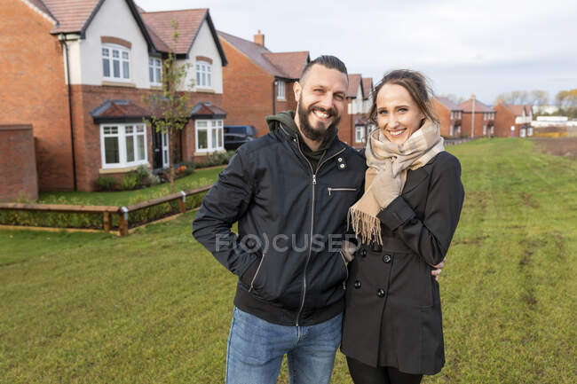 Couple heureux debout ensemble contre des maisons nouvellement construites — Photo de stock