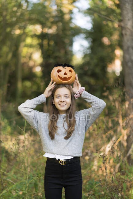 Ragazza giocosa che tiene la zucca di Halloween mentre si trova al parco — Foto stock