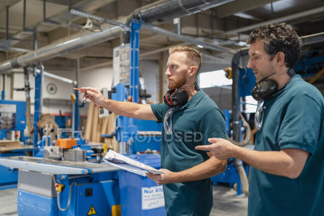 Two carpenters standing and talking in production hall — Stock Photo