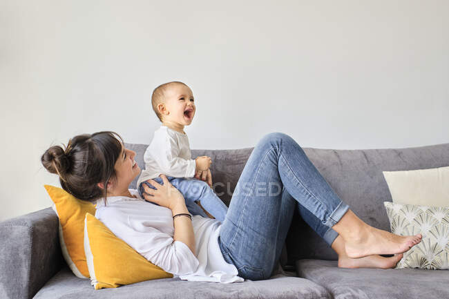 Mãe brincando com bebê filha no sofá — Fotografia de Stock