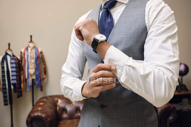 Hombre en chaleco gris sujeción camisa puño en sastres boutique - foto de stock