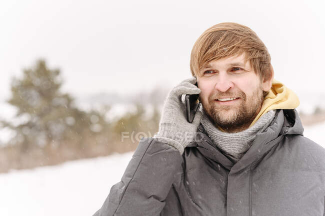 Close-up de sorrir homem adulto médio falando por telefone celular contra o céu limpo — Fotografia de Stock