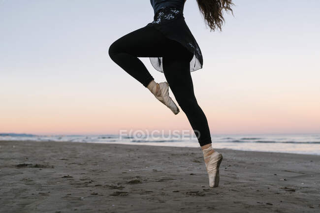 Female ballet dancer practicing at beach during sunset against sky — Stock Photo