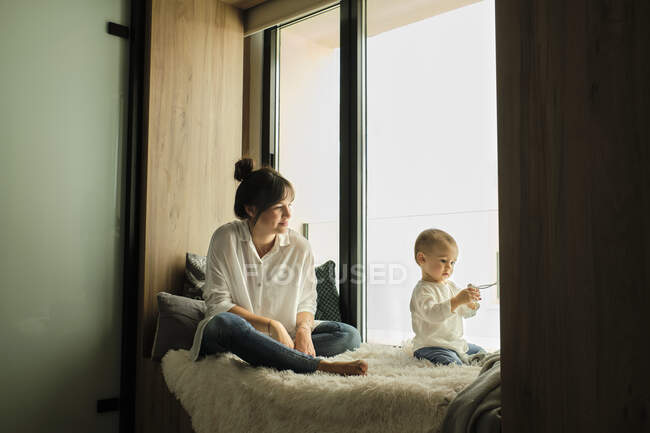 Мама сиділа біля вікна з донечкою. — стокове фото