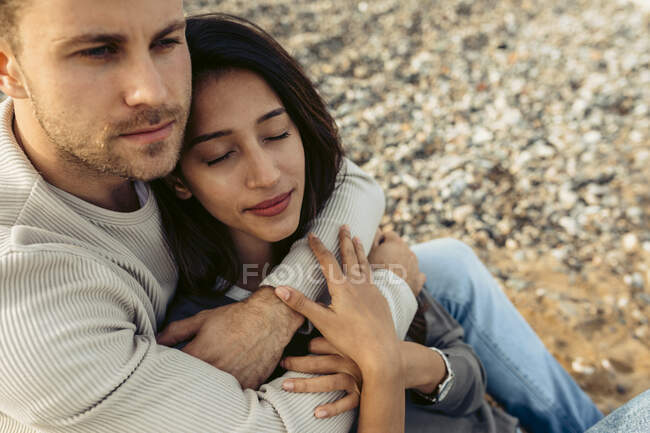 Giovane uomo abbracciare donna mentre guardando lontano in spiaggia — Foto stock