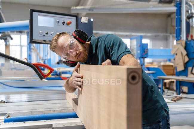 Carpenter measuring wooden plank in production hall — Stock Photo