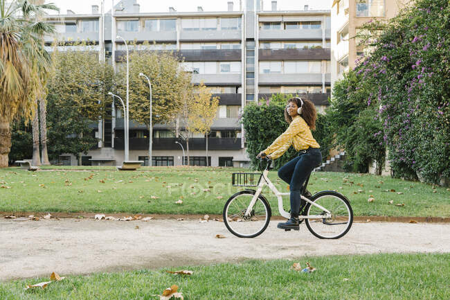 Giovane donna che ascolta musica mentre va in bicicletta sul sentiero — Foto stock