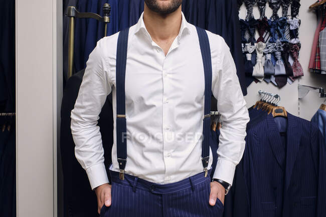 Cliente en camisa blanca y tirantes azules en sastres boutique - foto de stock