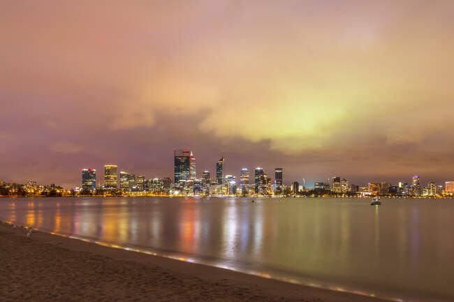 Australie, Perth, gratte-ciel du centre-ville vus de l'autre côté de la rivière Swan illuminés au crépuscule — Photo de stock