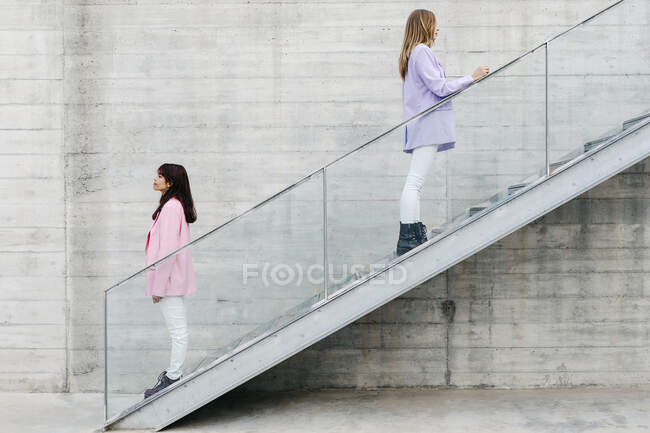 Young sisters showing back to each other while standing on steps — Stock Photo