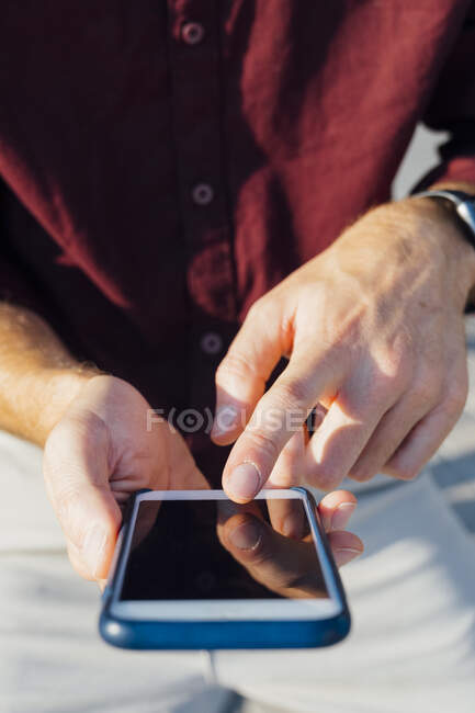 Businessman pointing at mobile phone screen while sitting outdoors - foto de stock