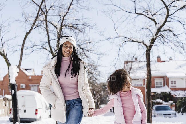Mutter und Tochter halten sich Händchen, während sie im Winter auf der Straße gehen — Stockfoto