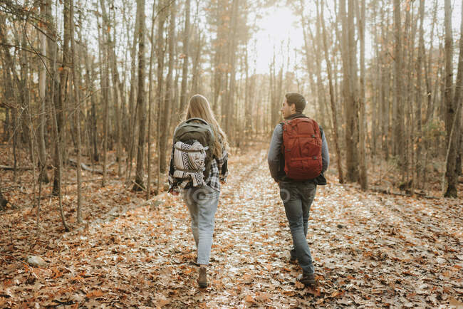 Young couple hiking with backpacks in autumn forest — Stock Photo