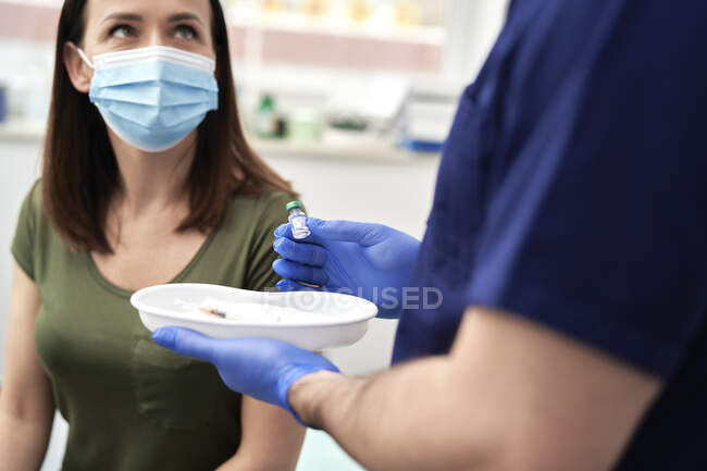 Paziente di sesso femminile con maschera facciale che discute con il medico prima di prendere la vaccinazione contro COVID-19 — Foto stock