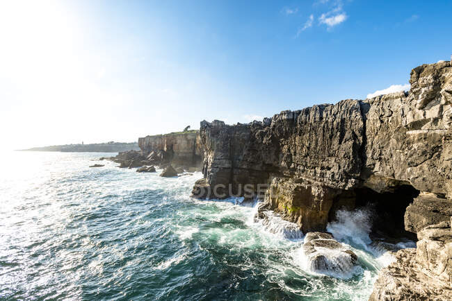 Sea waves crashing against cliffs with cave — Stock Photo