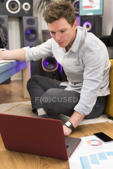 Mitte erwachsener Geschäftsmann arbeitet am Laptop, während er zu Hause sitzt — Stockfoto