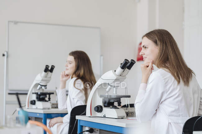 Vista dal retro di giovani ricercatori in camici bianchi in una classe di scienze — Foto stock