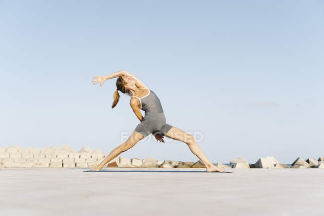 Deportista adulta haciendo yoga en alfombra de ejercicio - foto de stock