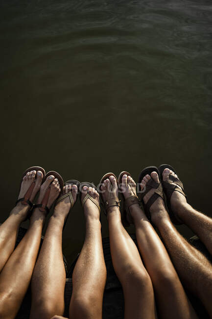 Family legs dangling over lake — Stock Photo