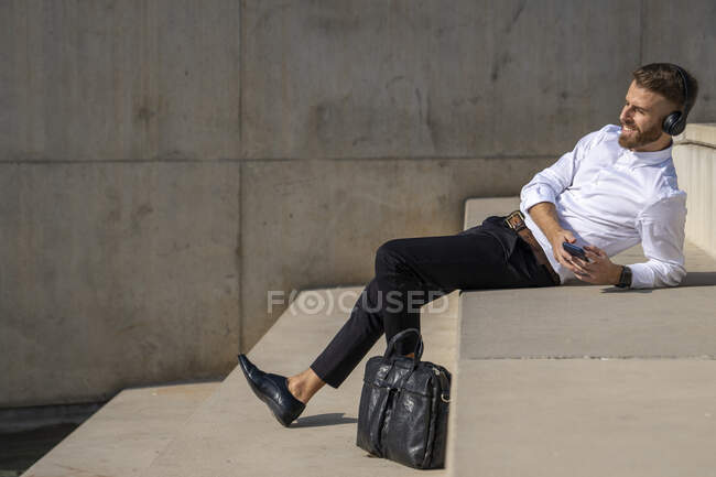 Businessman using mobile phone while relaxing on steps — Stock Photo
