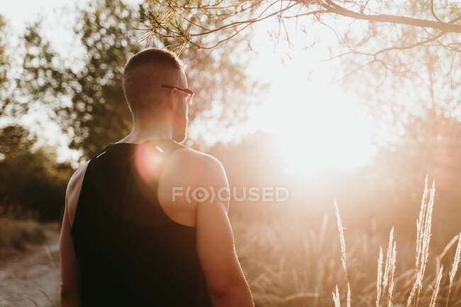 Männlicher Athlet steht bei Sonnenuntergang im Wald — Stockfoto