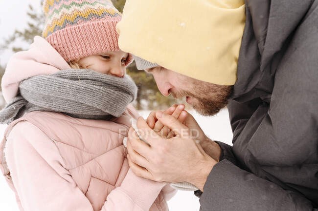 Primo piano delle fredde mani della figlia che riscalda il padre durante l'inverno — Foto stock