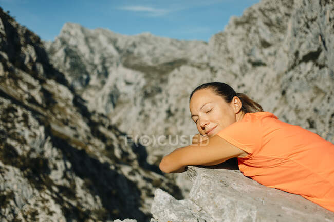 Donna con gli occhi chiusi rilassante sulla roccia al Cares Trail nel Parco Nazionale Picos De Europe, Asturie, Spagna — Foto stock