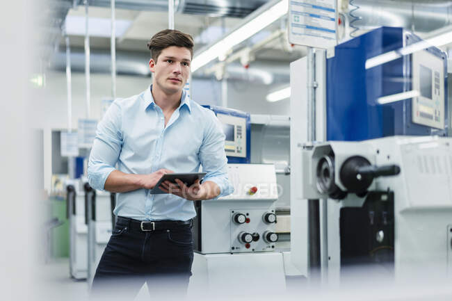 Young businessman holding digital tablet while working in industry — Stock Photo