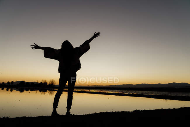 Junge Frau mit ausgestreckten Armen in der Abenddämmerung am ebro delta, Spanien — Stockfoto