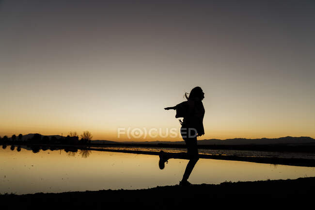 Young woman twirling on one leg during sunset at Ebro Delta, Spain - foto de stock