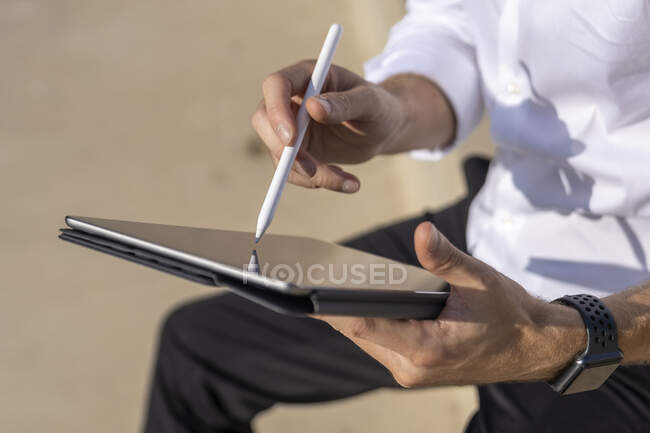 Empresário usando mesa digital enquanto sentado ao ar livre no dia ensolarado — Fotografia de Stock