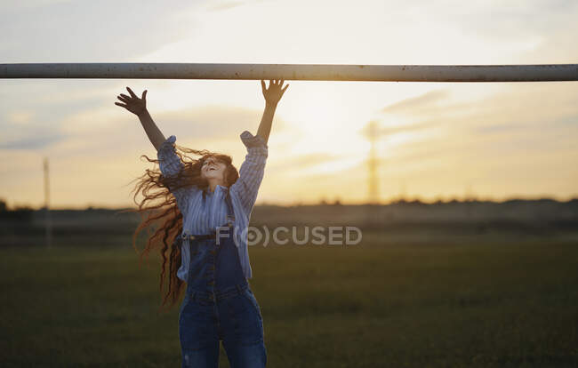 Felice donna matura con i capelli lunghi saltare contro il cielo durante il tramonto — Foto stock