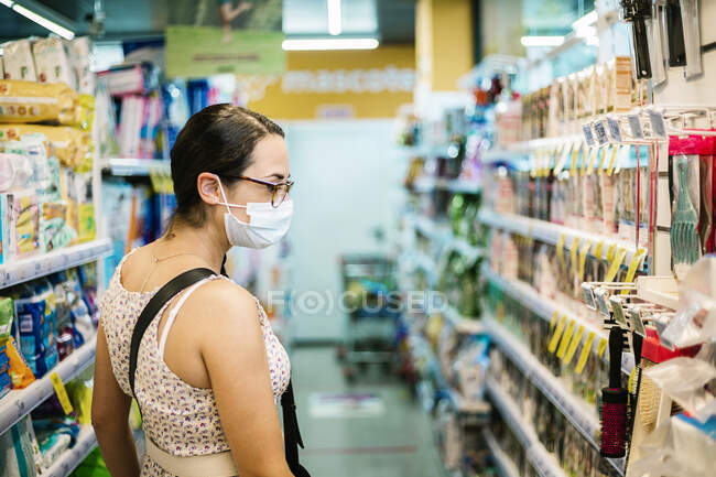 Серед дорослої жінки з захисною маскою в супермаркеті. — стокове фото