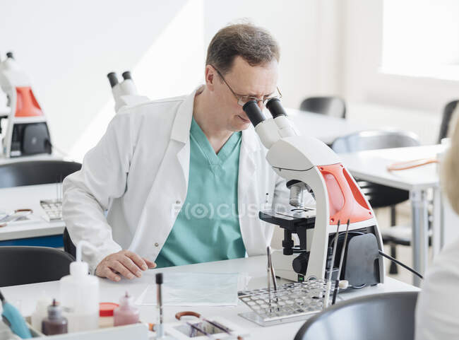 Investigador senior trabajando con microscopio en laboratorio - foto de stock
