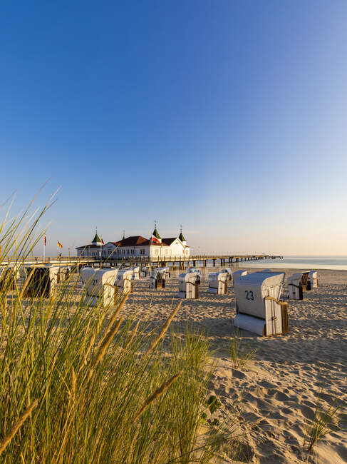 Alemanha, Mecklemburgo-Pomerânia Ocidental, Ahlbeck, cadeiras de praia com capuz na praia costeira arenosa com casa de banho no fundo — Fotografia de Stock