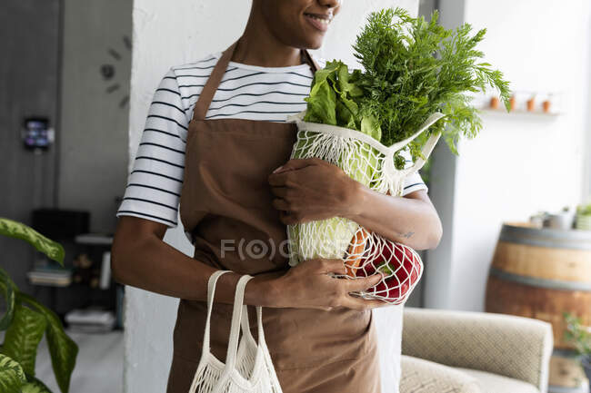 Mulher bonita em avental carregando líquido com legumes frescos — Fotografia de Stock