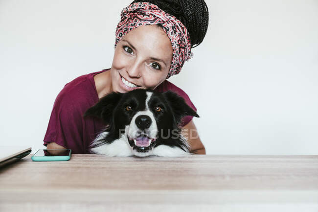 Smiling woman embracing Border Collie against white wall at home — Stock Photo