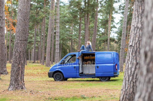 Metà donna adulta guardando altrove mentre seduto sul tetto del furgone a Cannock Chase — Foto stock