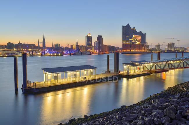 Germany, Hamburg, Northern bank of Elbe at dawn with Elbphilharmonie and city skyline in background — Stock Photo