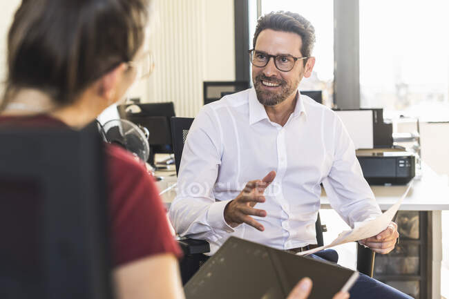 Smiling businessman planning with colleague using digital tablet sitting at office — Stock Photo