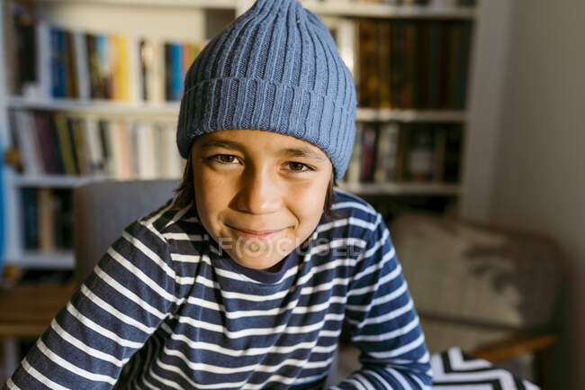 Sonriente niño usando sombrero de punto en casa - foto de stock