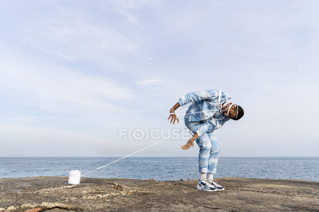 Молодий чоловік у мотузці, що тікає, стоячи навпроти неба. — стокове фото