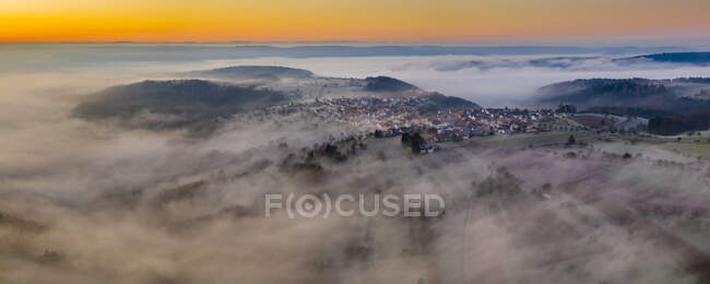Alemanha, Baden-Wurttemberg, Berglen, vista de zangão da aldeia envolta em névoa espessa ao amanhecer — Fotografia de Stock