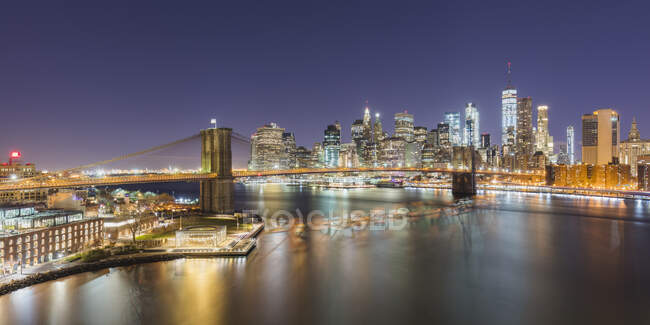 USA, New York, New York City, Brooklyn Bridge and Lower Manhattan skyline illuminated at night — Stock Photo