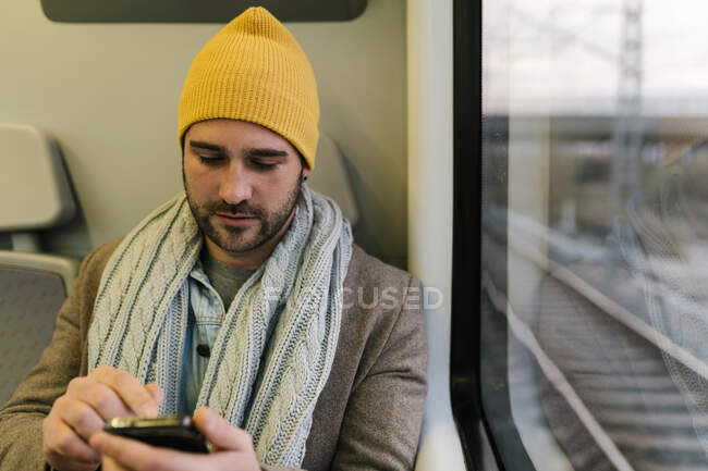 Homem usando telefone celular enquanto sentado no trem — Fotografia de Stock