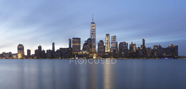 Usa, new york, new york city, lower manhattan mit einem Welthandelszentrum, das im Morgengrauen über dem Fluss erleuchtet wird — Stockfoto