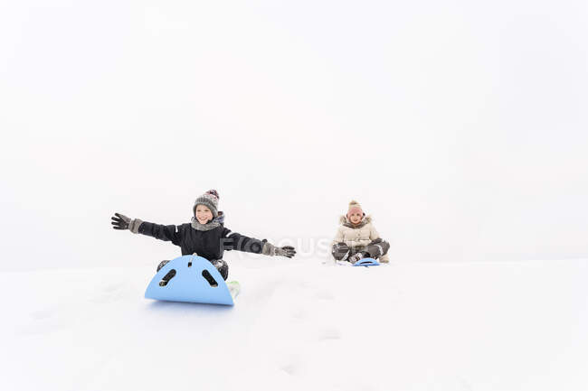 Irmã brincalhão e irmão trenó na colina coberta de neve — Fotografia de Stock