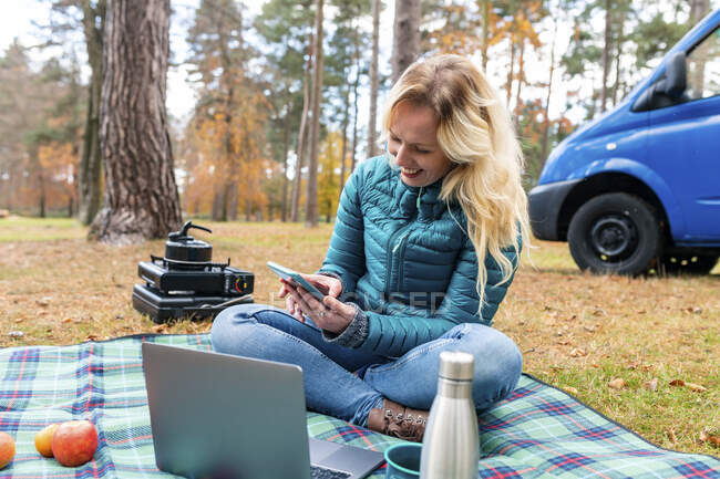 Donna sorridente utilizzando il telefono cellulare durante il campeggio a Cannock Chase — Foto stock